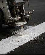 Utilaj de marcaje rutiere aplicând vopsea albă pe carosabil